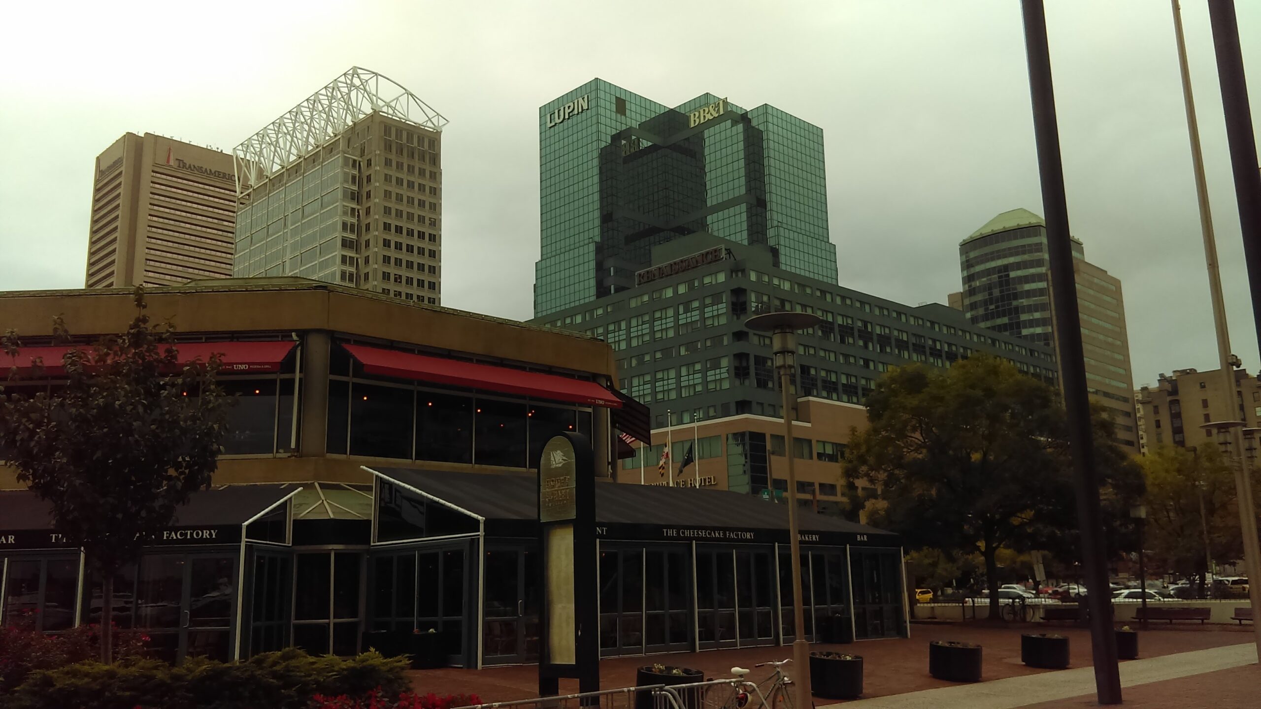 Cityscape featuring modern high-rise buildings and a restaurant with outdoor seating. Highlights urban architecture and dining options.