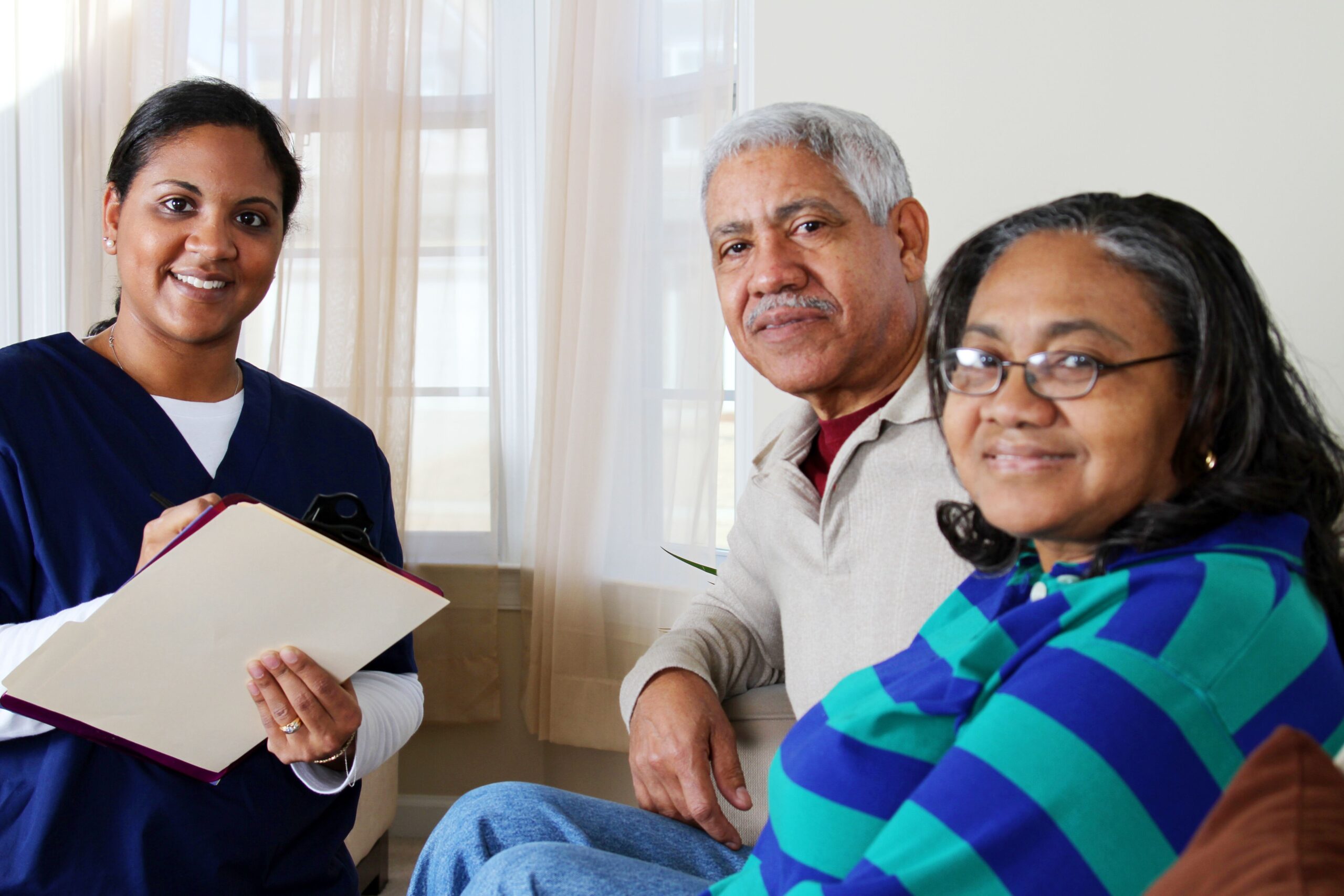 Healthcare professional engaged with two older adults in a warm, inviting setting. The scene highlights the importance of patient care and support.